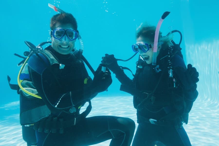 A buddy pair holding hands mid-water