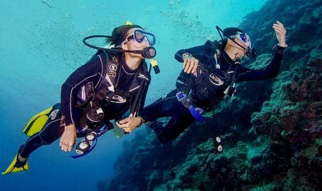 Two divers on their first boat dive, side by side over the reef