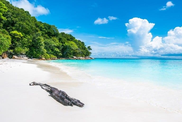 A white sand bay opening onto flat turquoise water