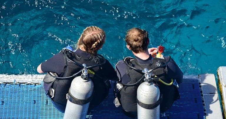 Two divers kitted up on the jetty before a dive