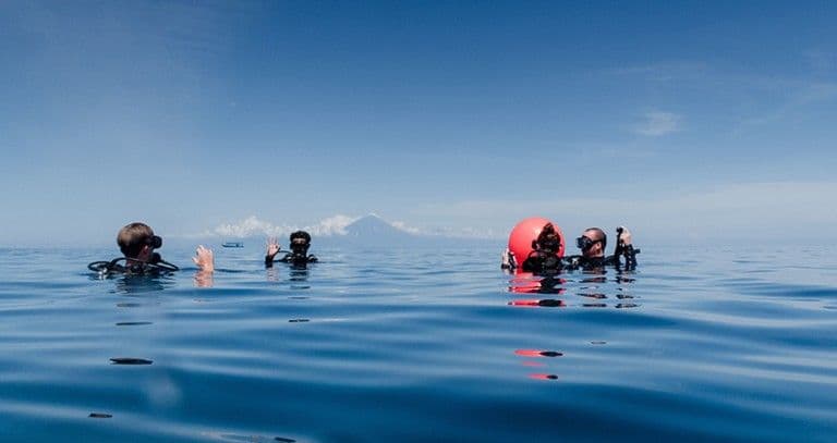 Divers waiting at the surface beside a marker buoy