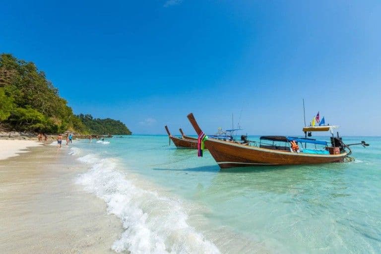 A longtail boat pulled up on an empty beach